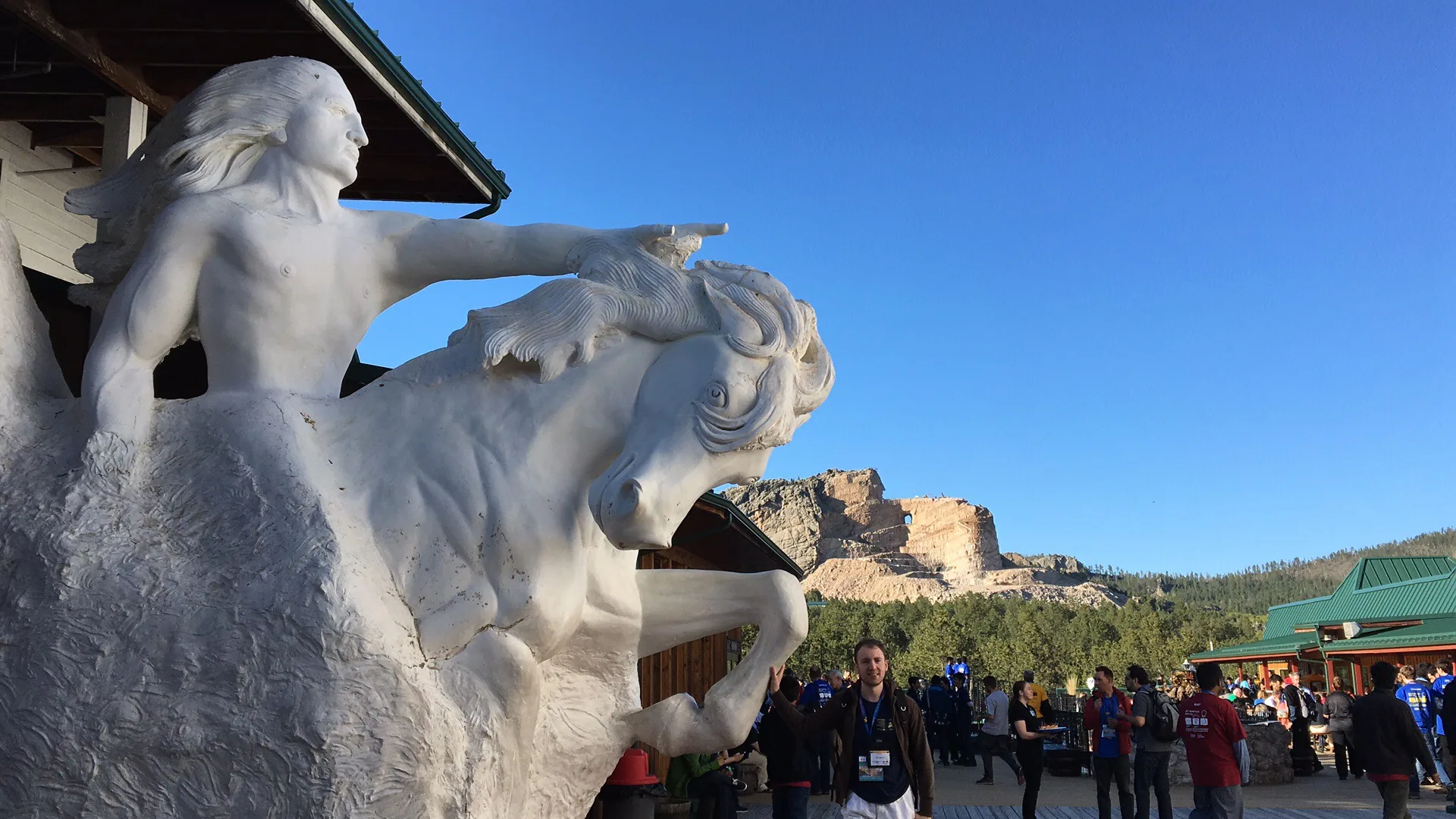 A model of the completed Crazy Horse Memorial in front of the unfinished mountain carving